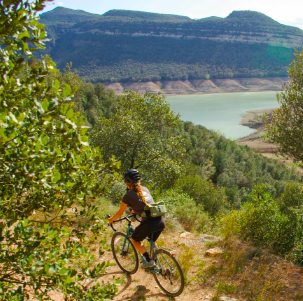 Mujer en bicicleta de gravel a orillas de un lago en Cataluña.