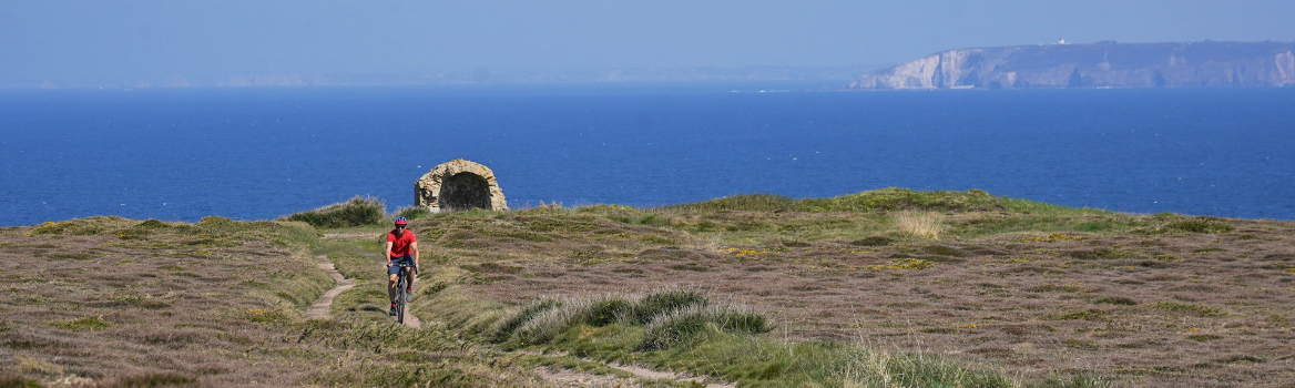 Homme à vélo gravel sur une piste qui surplombe la mer sur la côte Bretonne du Finistère en France