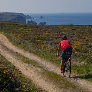 Un hombre en bicicleta de gravel por una pista que bordea los acantilados del Finistère, en Bretaña